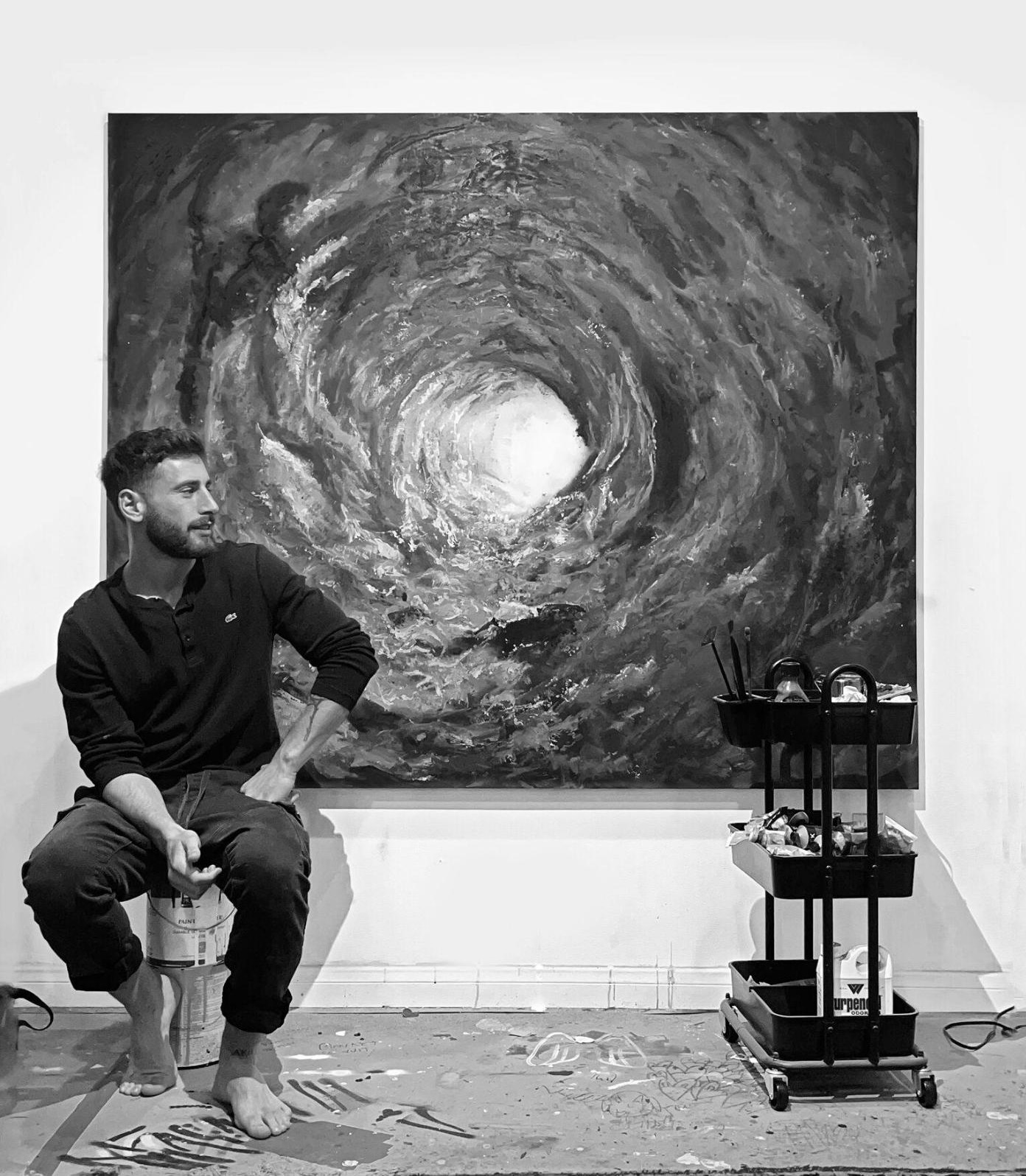 Alex Partouche seated in the studio in front of a large vortex painting